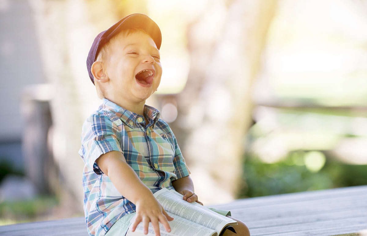 Child with Book in their Hand Laughing Child with Book in their Hand Laughing